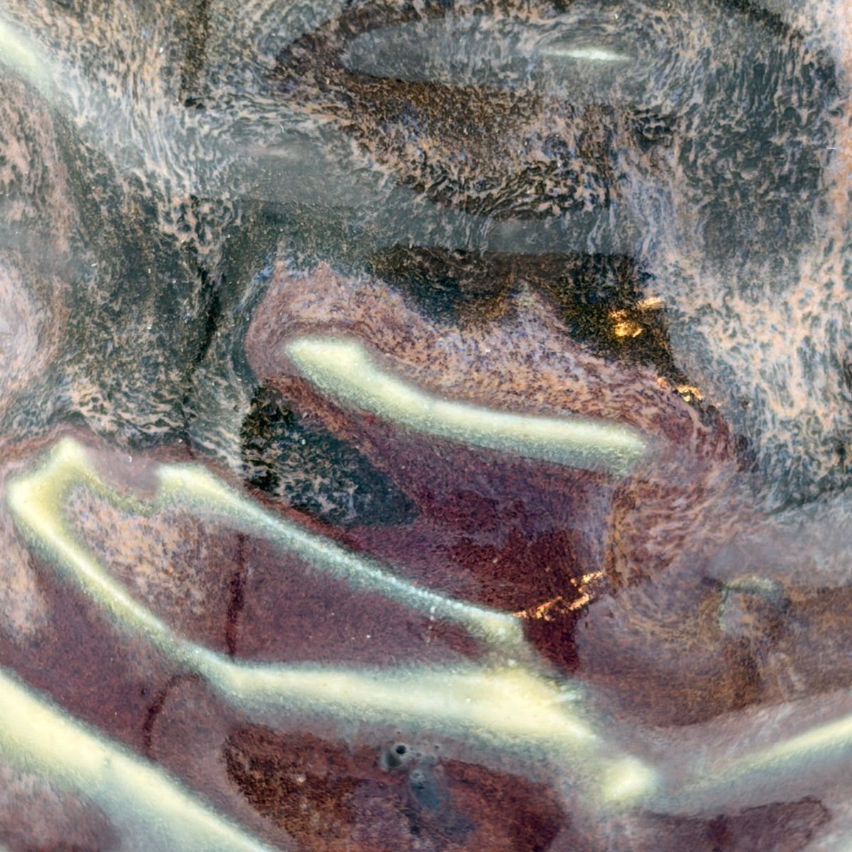 Abstract textured surface with flowing marbled bands in gray, brown, cream, and muted purple tones.