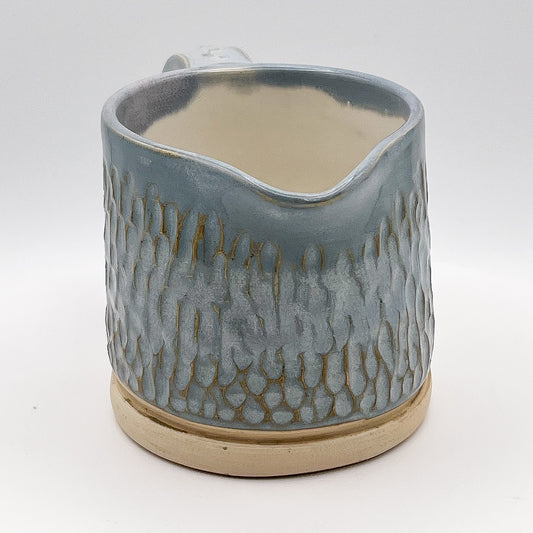 Ceramic mug with textured design on a white background