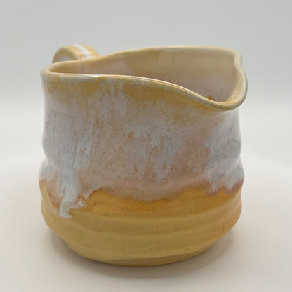 Yellow ceramic pitcher with a textured surface on a white background