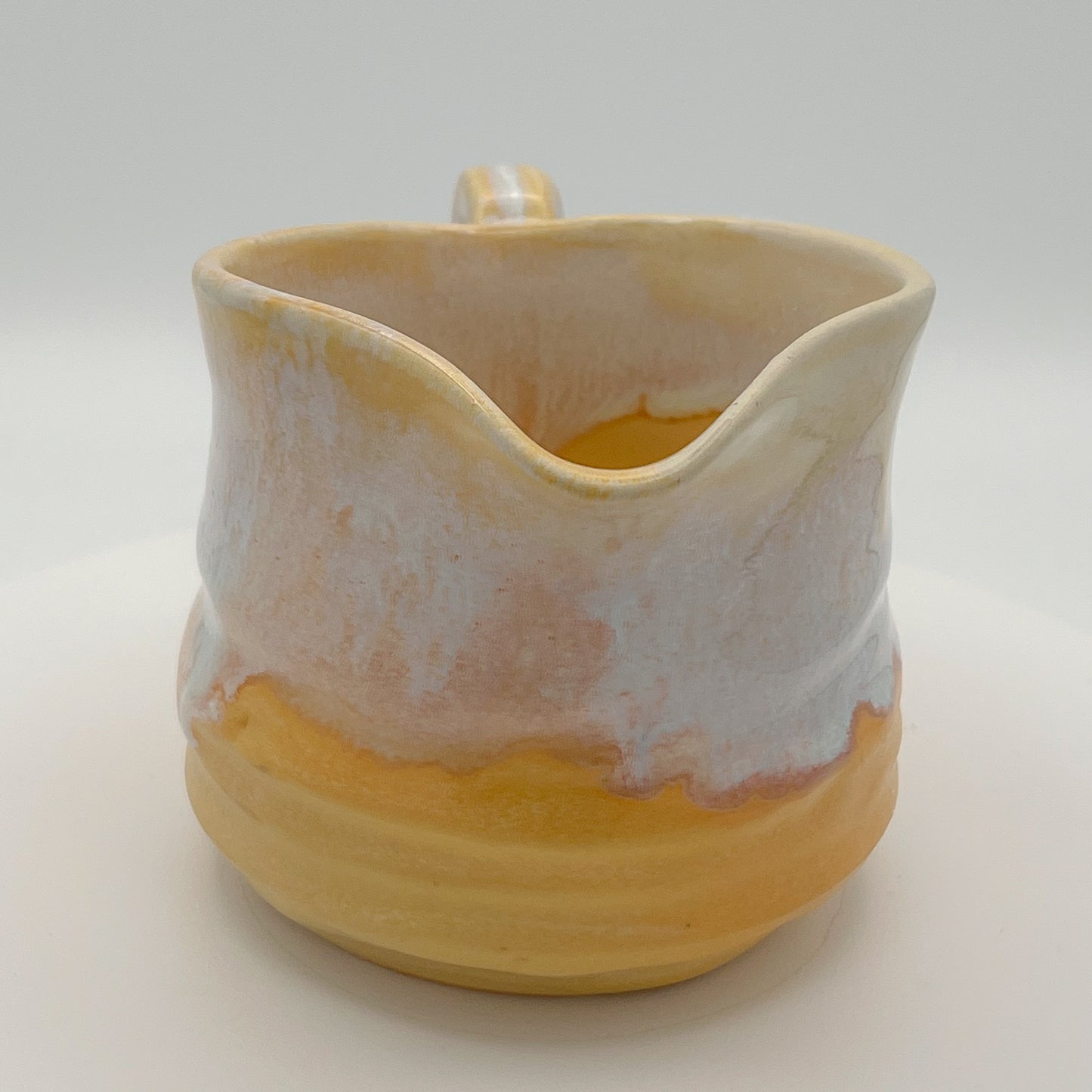 Ceramic pitcher with a gradient from beige to yellow on a white background