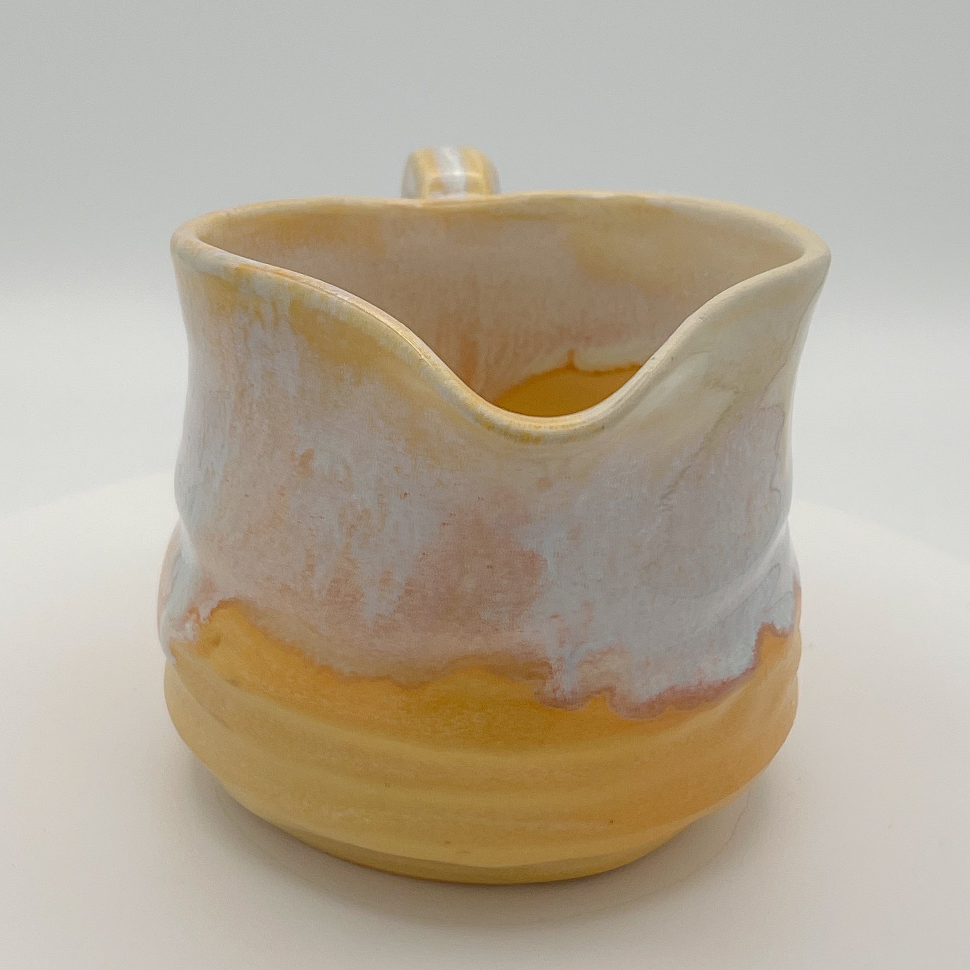 Ceramic pitcher with a gradient from beige to yellow on a white background