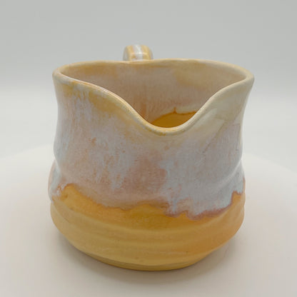 Ceramic pitcher with a gradient from beige to yellow on a white background