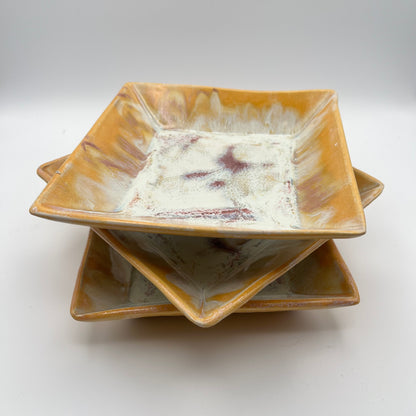 Stack of ceramic square bowls with a textured brown rim on a white background