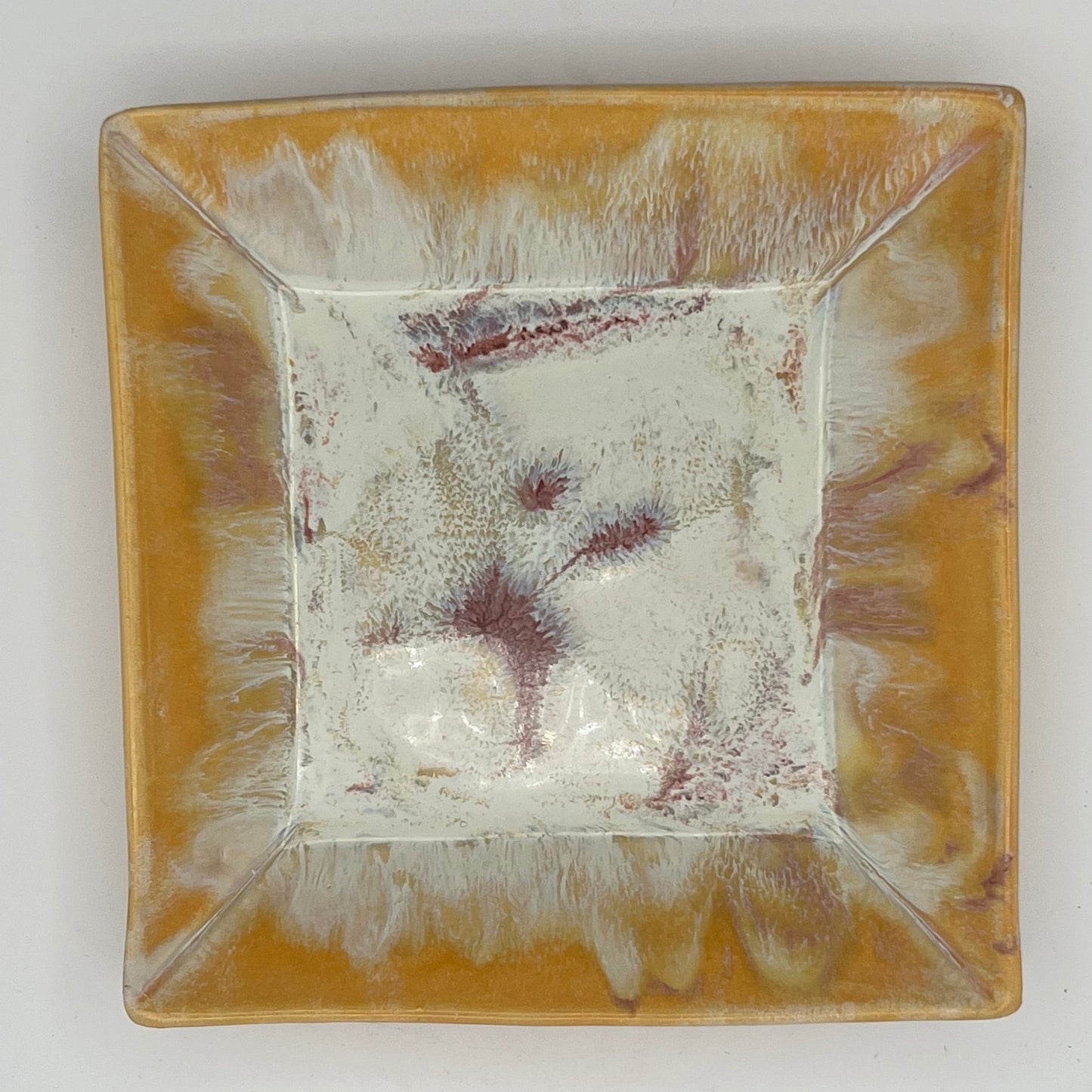 Square ceramic plate with textured surface on a white background