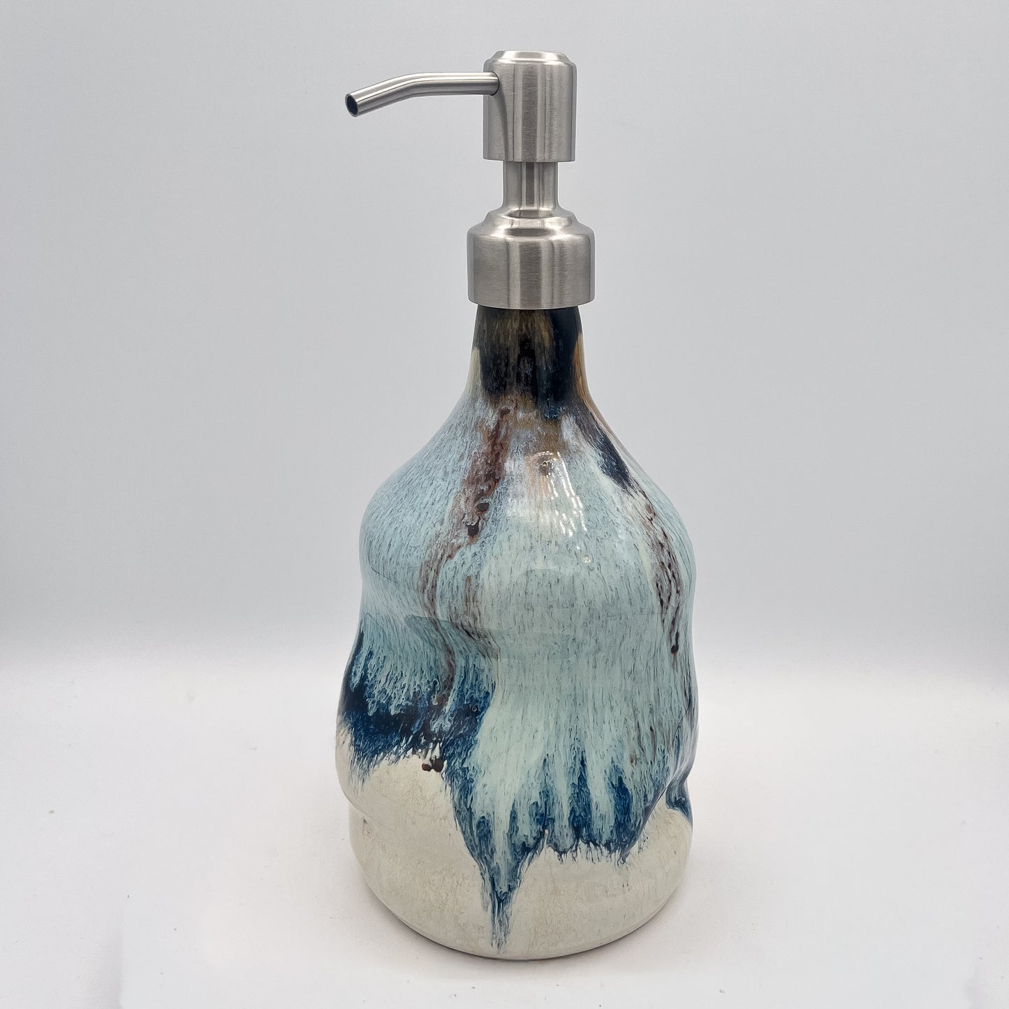 Handmade ceramic soap dispenser with blue and white flowing glaze and stainless steel pump