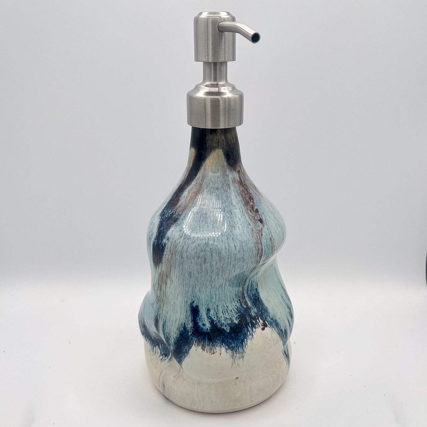 Handmade ceramic soap dispenser with blue and white flowing glaze and stainless steel pump