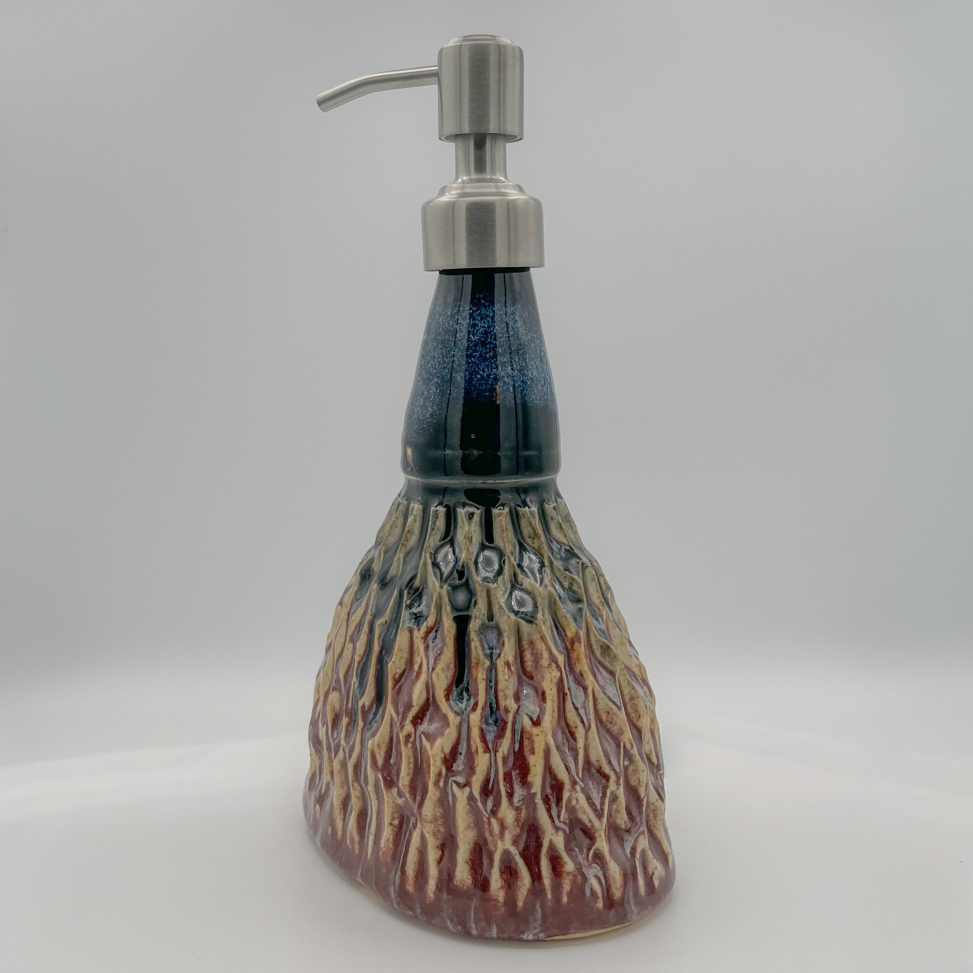Ceramic soap dispenser with a textured design on a white background