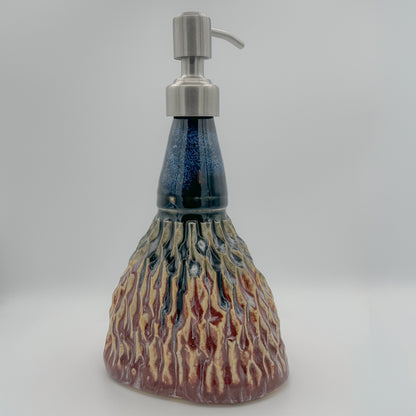 Ceramic soap dispenser with textured design and metallic pump on a gray background