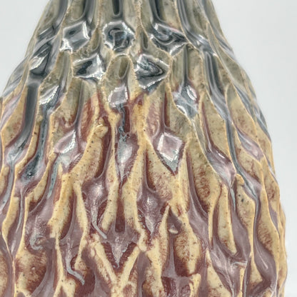 Close-up of a textured ceramic vase with brown and silver patterns on a white background