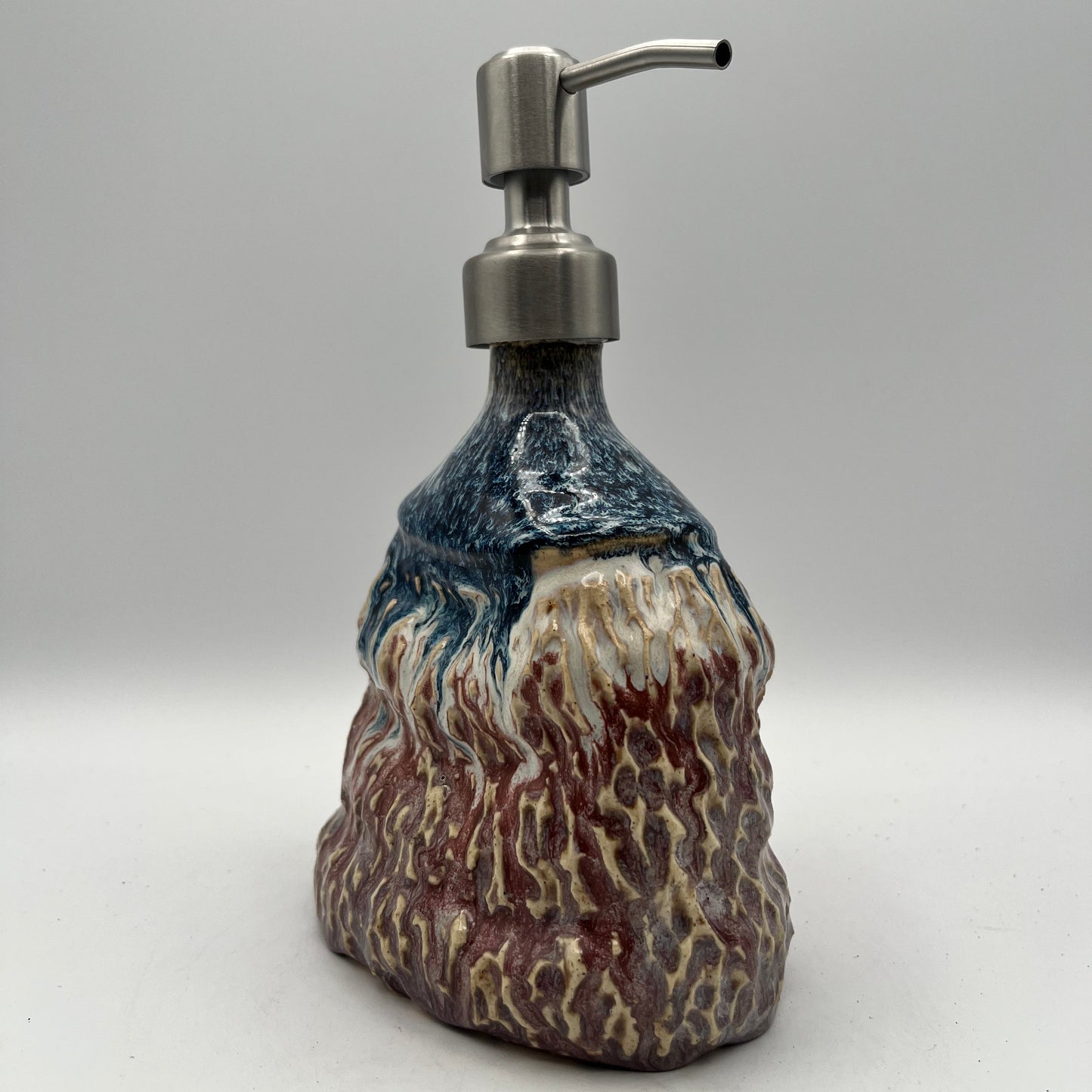 Decorative soap dispenser with a textured design on a white background