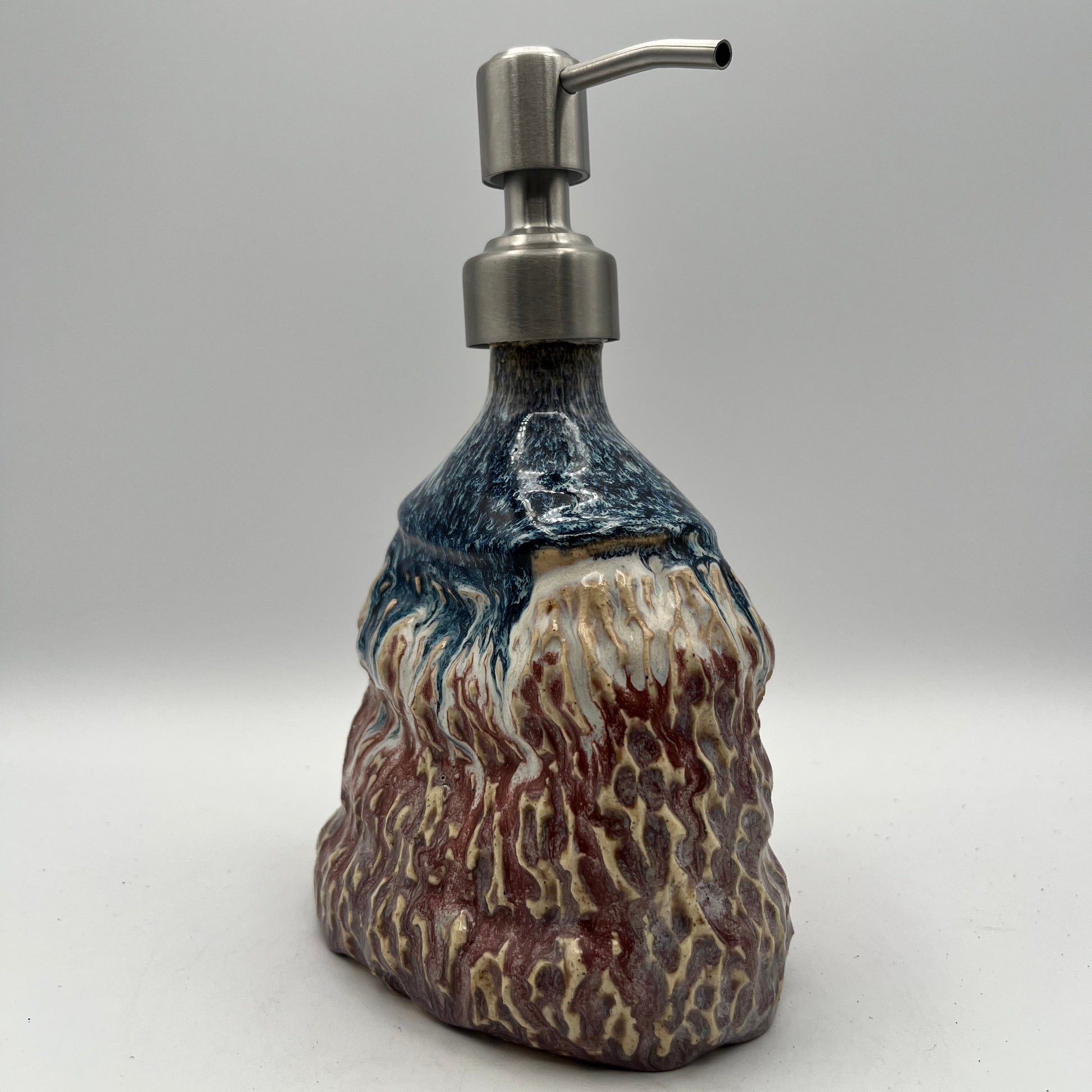 Decorative soap dispenser with a textured design on a white background