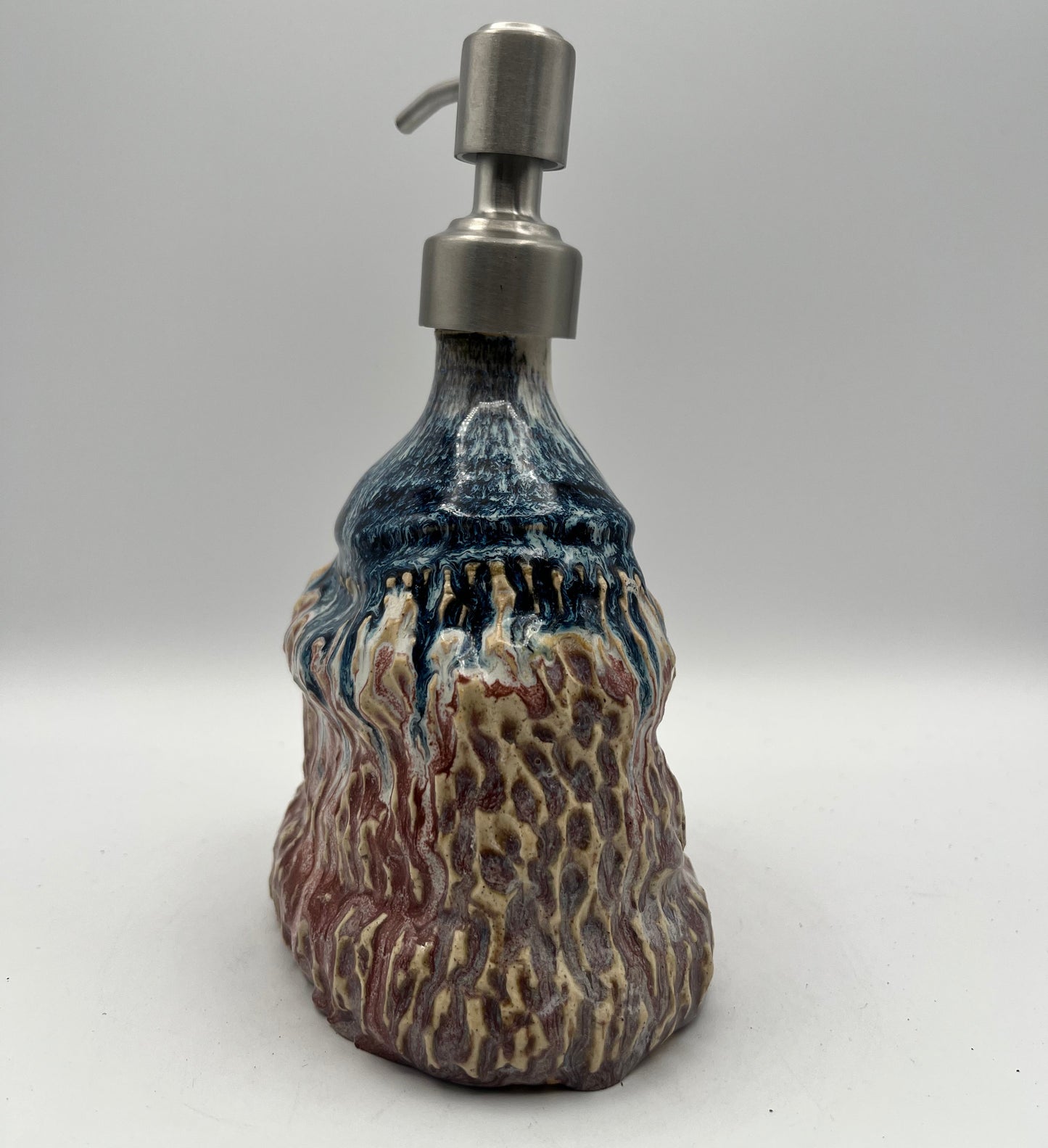 Stoneweaar soap/lotion dispenser with a textured surface on a white background