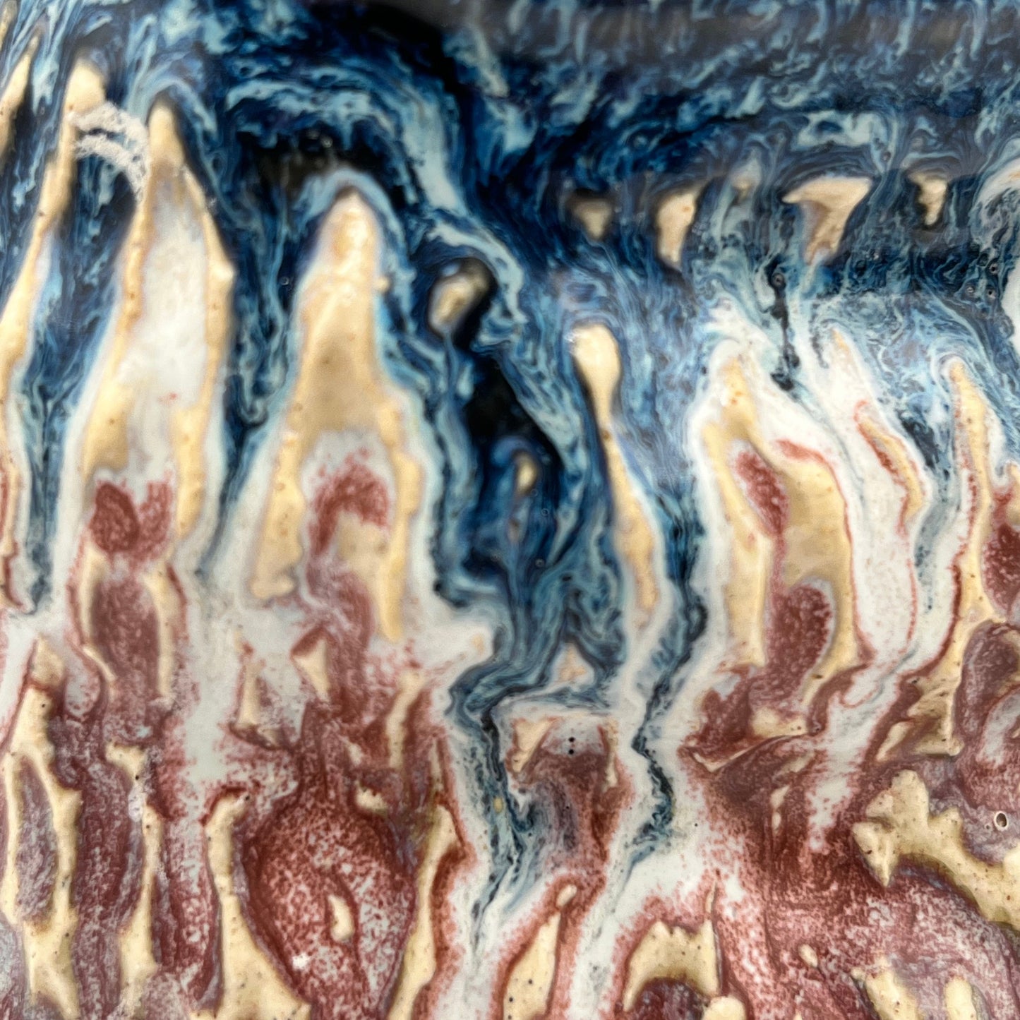 Close-up of a marbled ceramic surface with blue, brown, and beige colors.