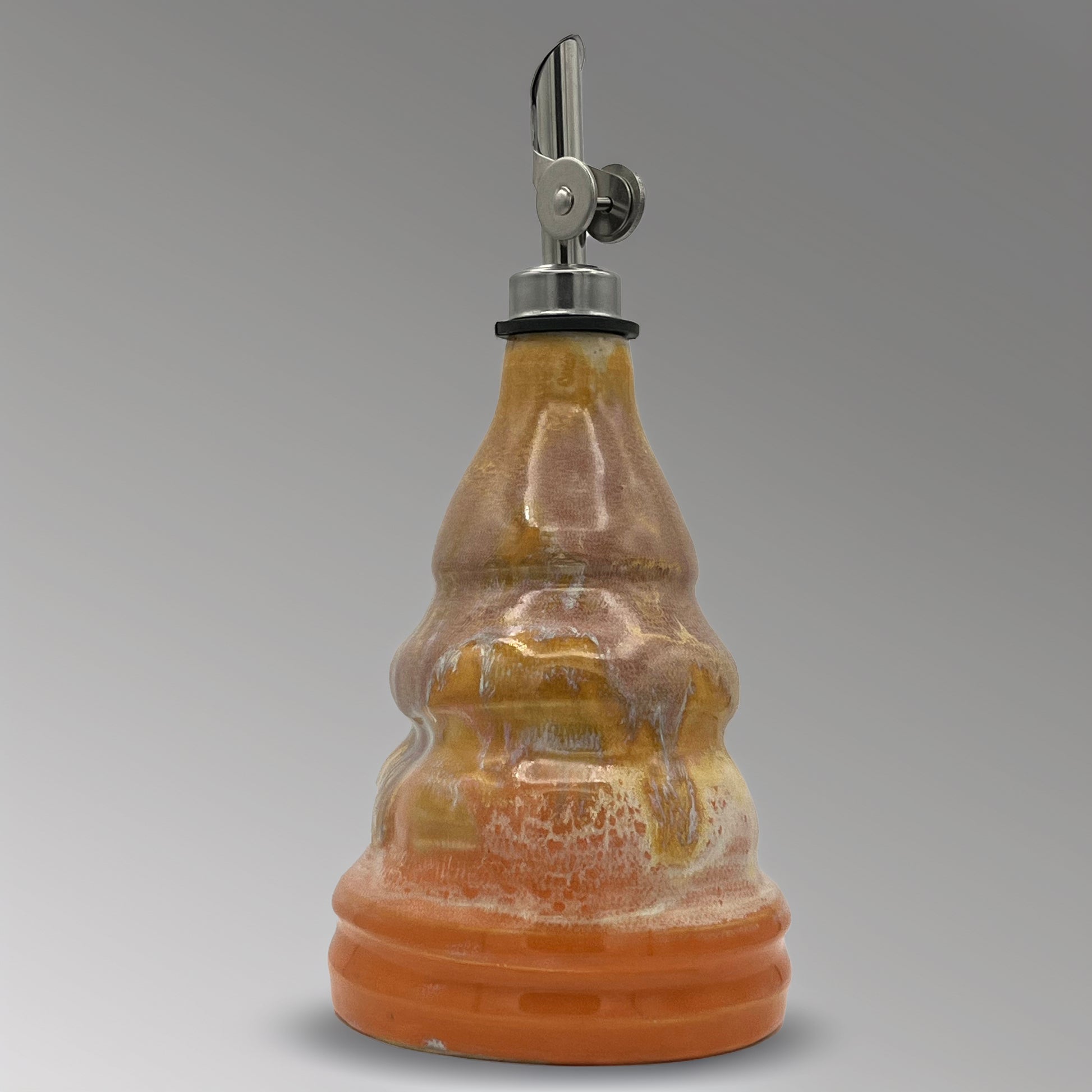Ceramic oil decanter with a metal cap on a gray background