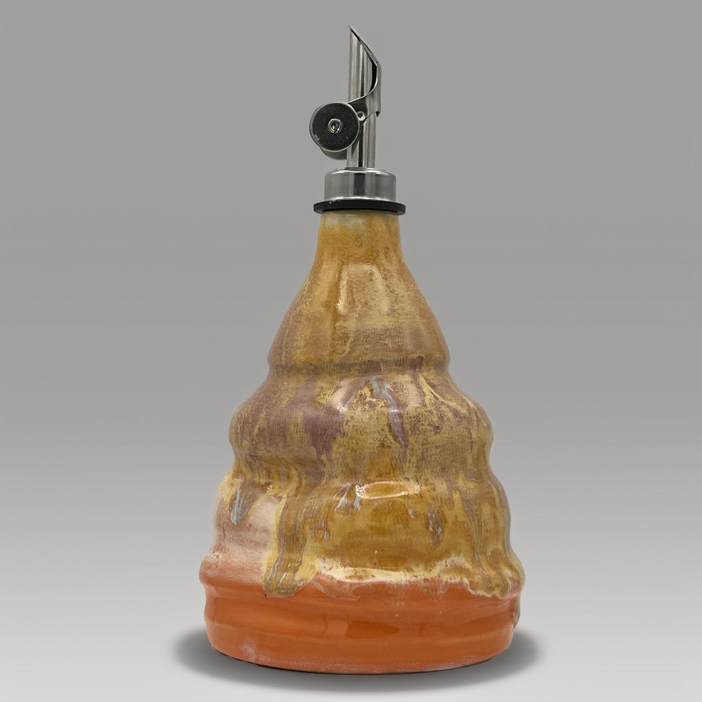 Ceramic oil decanter with a metal cap on a gray background