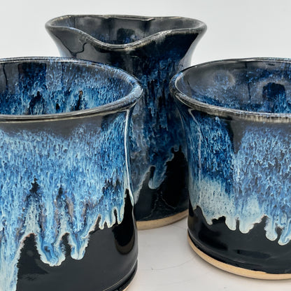 Three ceramic cups with blue and black glaze on a white background