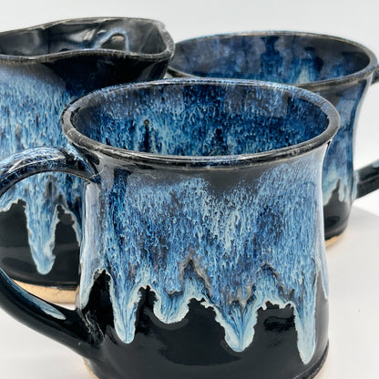 Three ceramic mugs with blue and black glaze on a white background