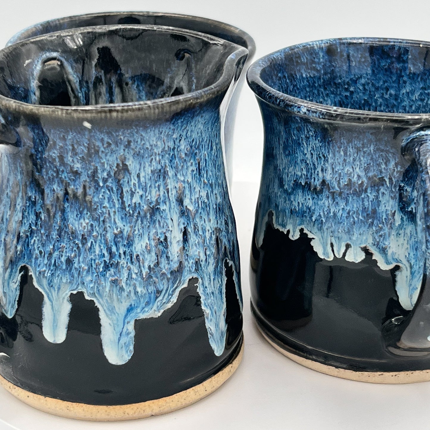 Two ceramic containers with blue and black glaze on a white background