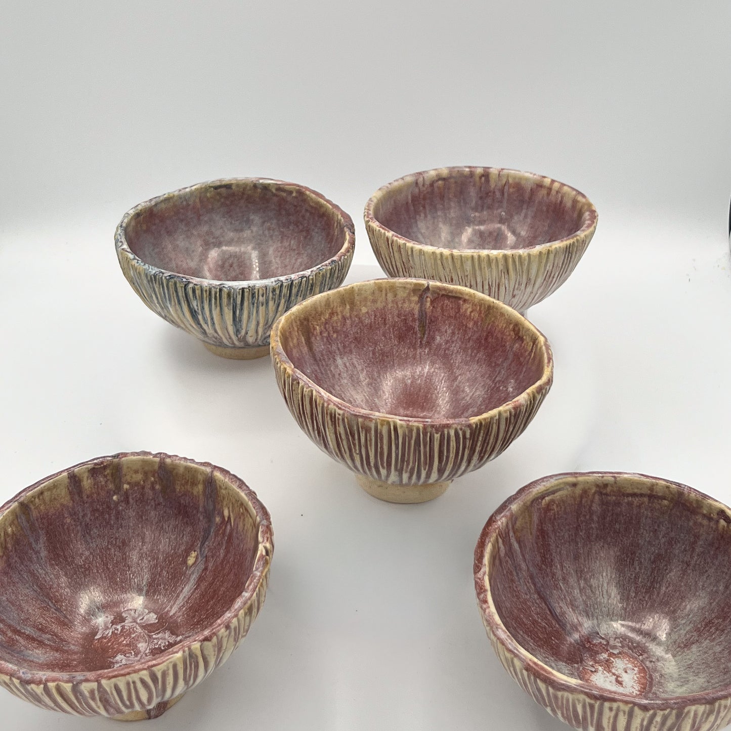 Set of five ceramic bowls with textured surfaces on a white background