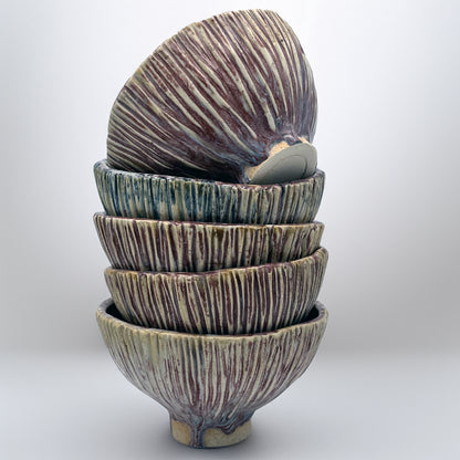 Stack of ceramic bowls with textured surface on a white background