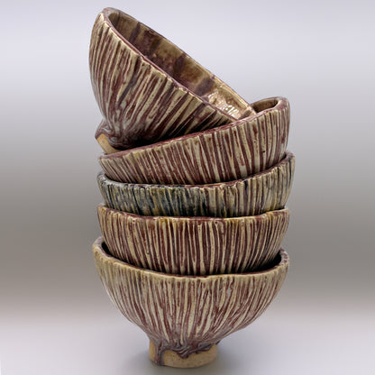 Stack of ceramic bowls with textured surface on a light gray background