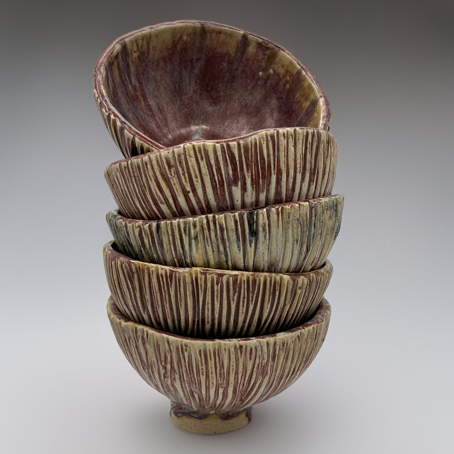 Stack of brown ceramic bowls with textured surface on a gray background