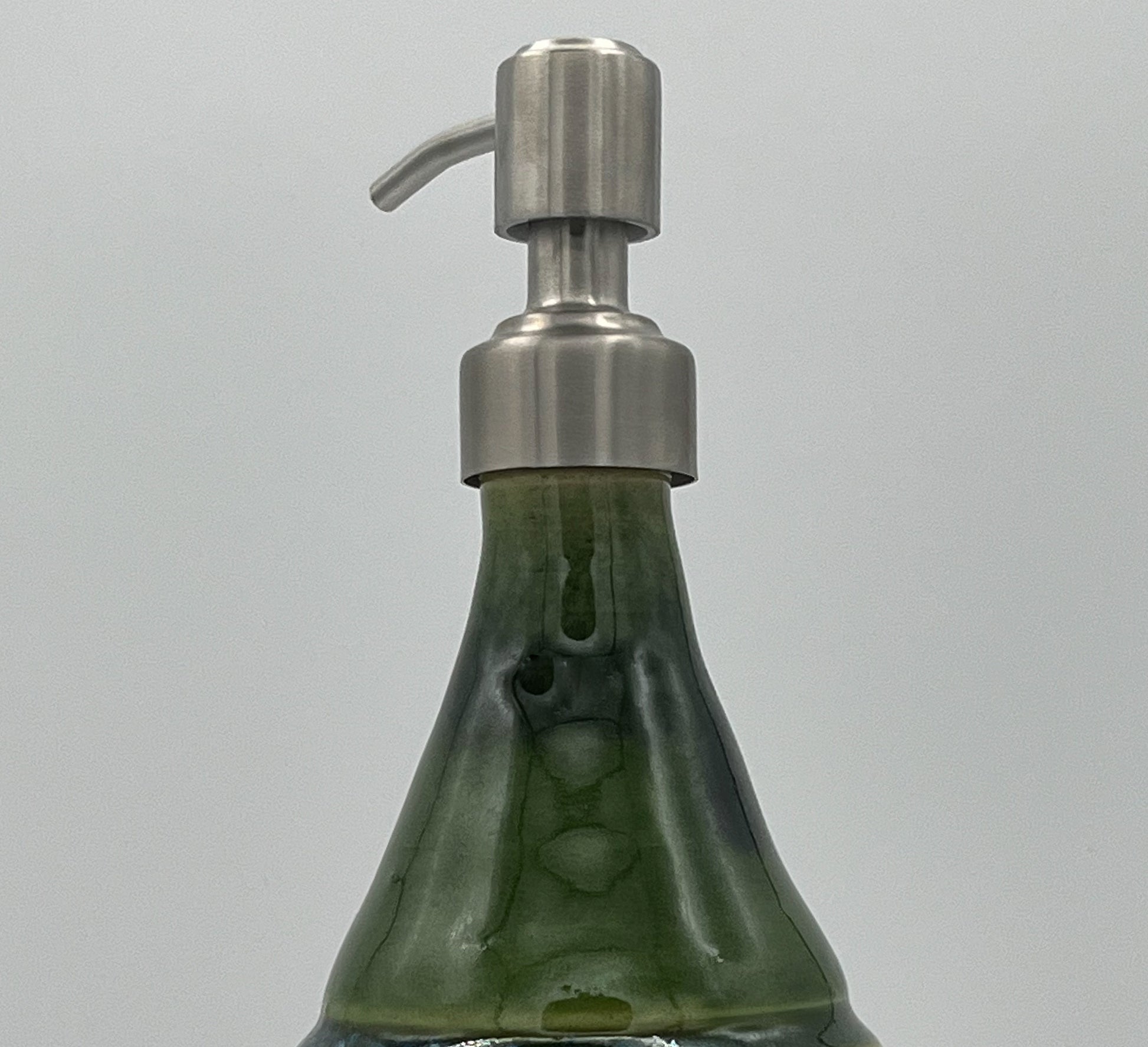Green soap dispenser with a metallic pump on a gray background