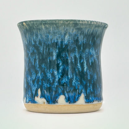 Ceramic cup with blue and beige glaze on a white background