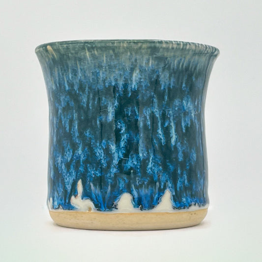 Ceramic cup with blue and beige glaze on a white background
