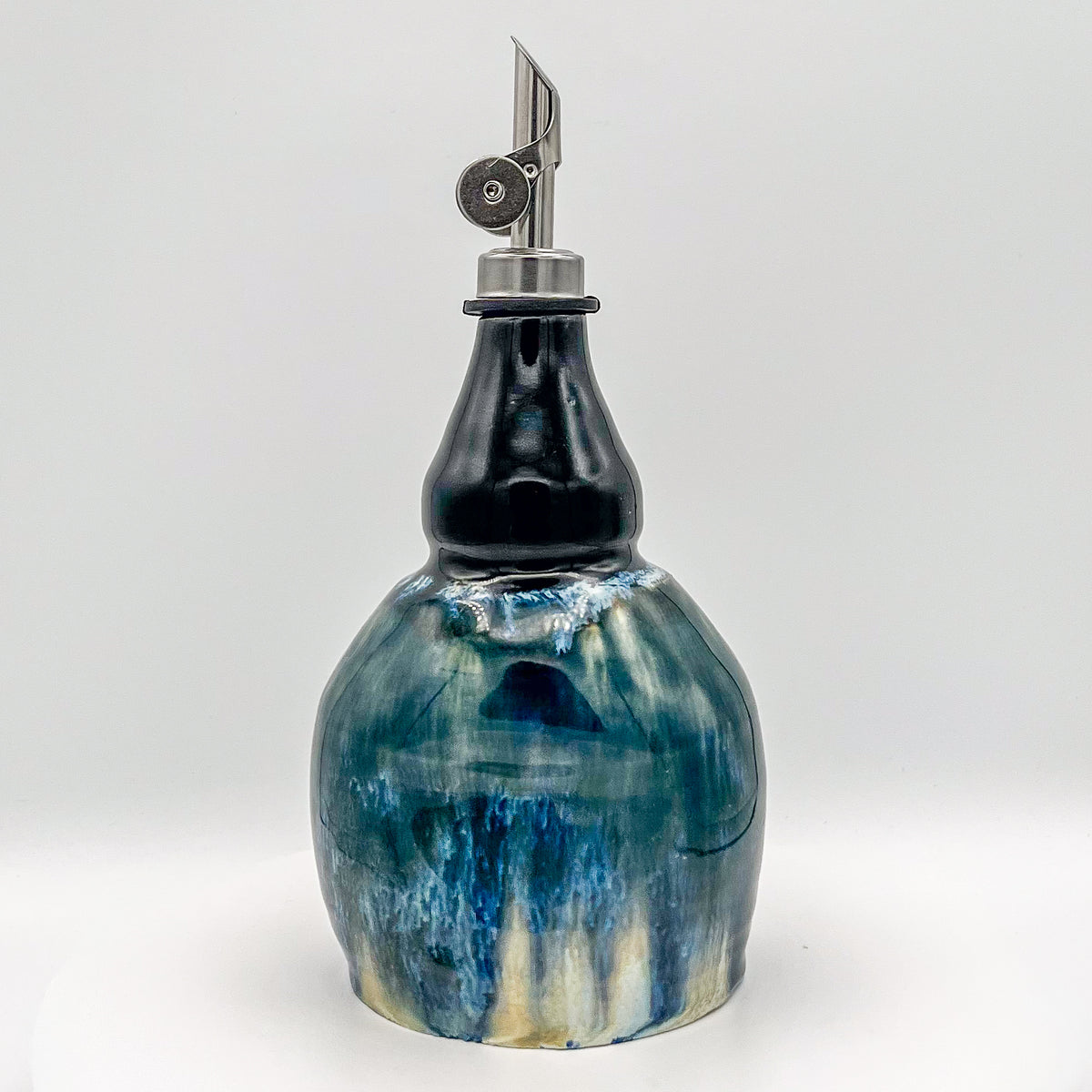 Decorative oil bottle with blue and white marbled design on a white background