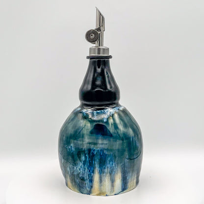 Decorative oil bottle with blue and white marbled design on a white background