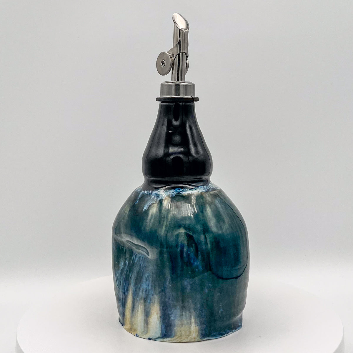 Decorative ceramic bottle with a metal dispenser on a white background