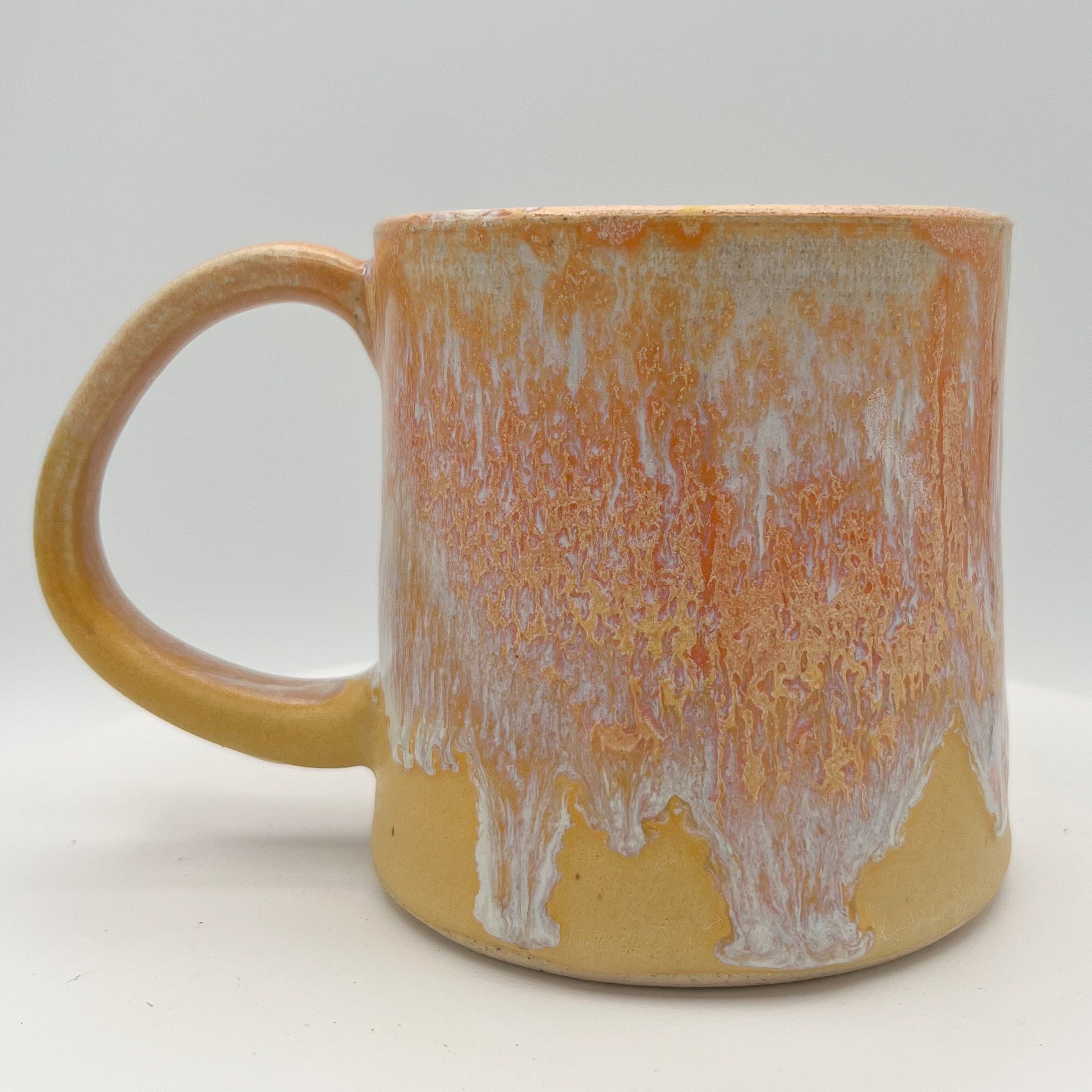Handmade ceramic mug with peach and cream glaze and comfortable handle