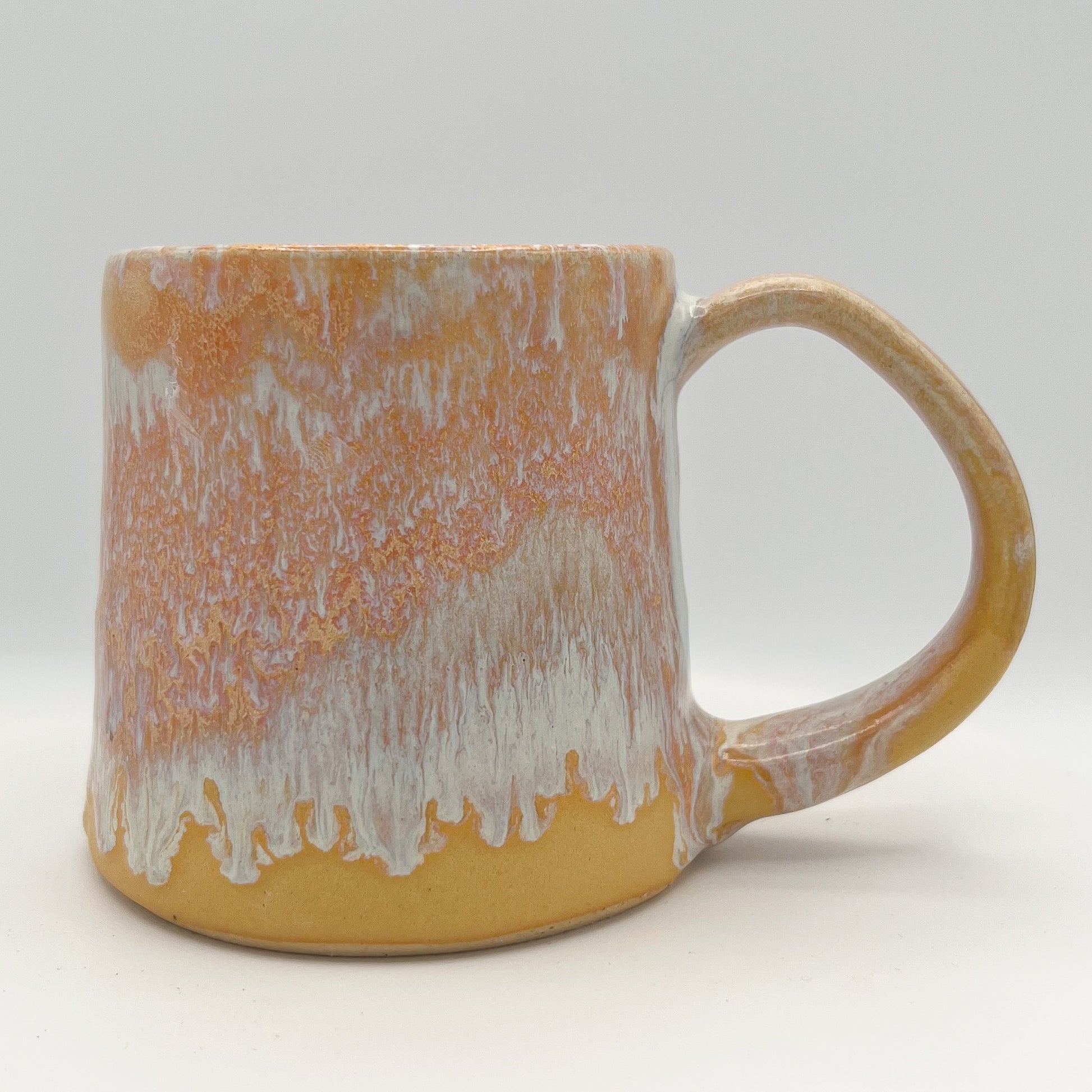 Handmade ceramic mug with peach and cream glaze and comfortable handle