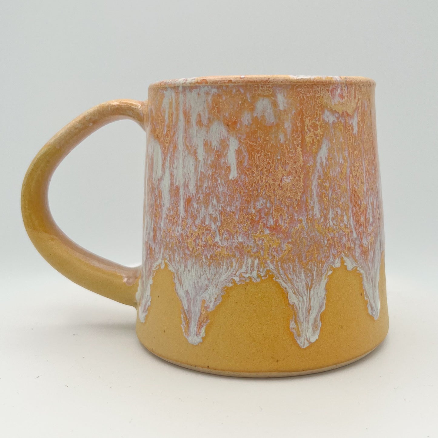 Handmade ceramic mug with peach and cream glaze and comfortable handle