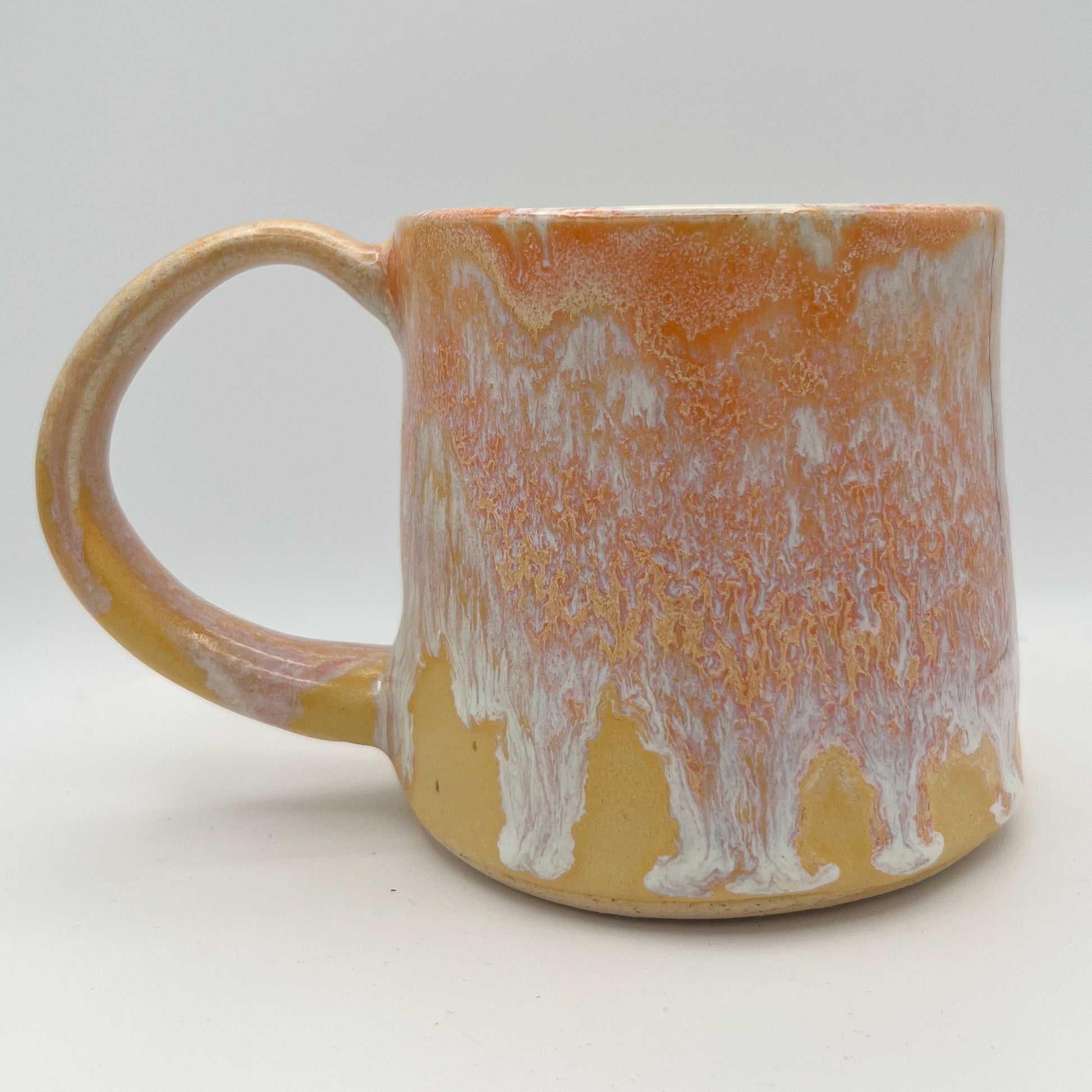 Handmade ceramic mug with peach and cream glaze and comfortable handle